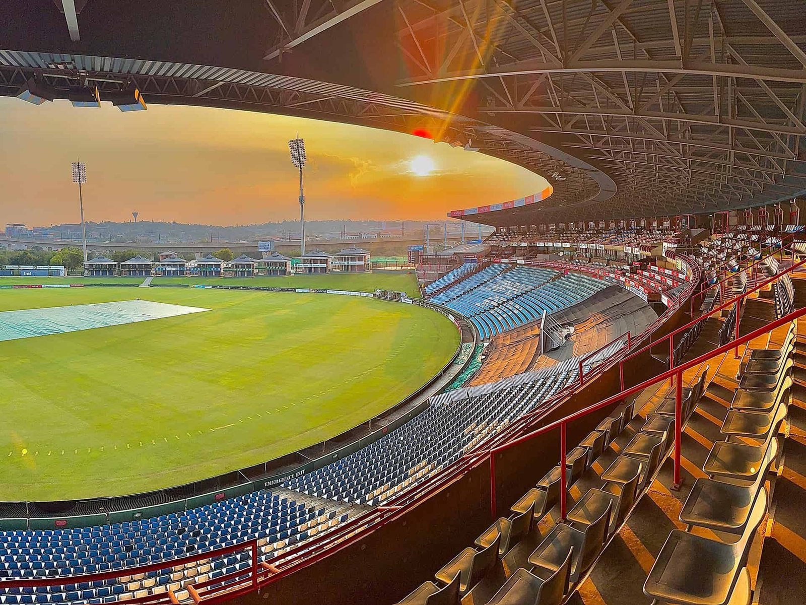 Sunset over SuperSport Park in Centurion, with the outfield, covered grandstand and floodlights in view.